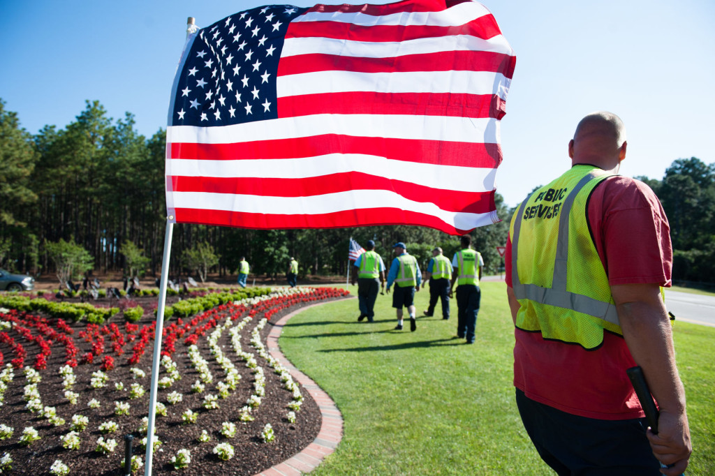 Public Service worker J.C. Clark (right) works with others as they post flags at the triangles off the large traffic circle on Friday, May 22, 2015 in Pinehurst, North Carolina. The workers posted flags down Midland Road, all triangles of the large traffic circle, a smaller circle near Pinehurst Resort and Marshall Park, totaling 125 American Flags for the Memorial Holiday weekend.