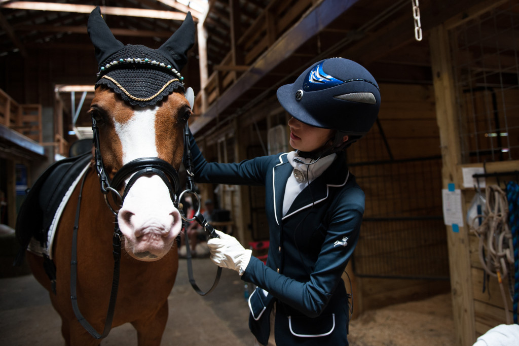Fourteen-year-old Lili Nabhan of Virginia Beach, Virginia  checks her horse Sb Heritage and his bridle before leaving the barn to ride in her First Level Test 3 in ring C during the Dressage in the Sandhills Horse Show at the Pinehurst Harness Track on Friday, May 8, 2015 in Pinehurst, North Carolina.
