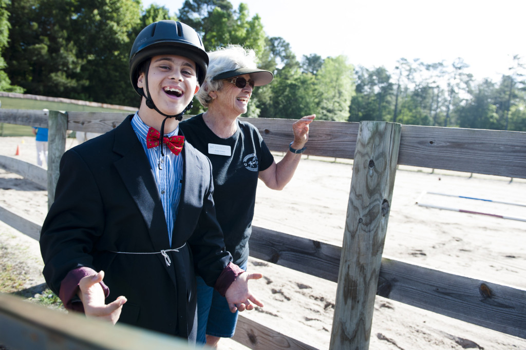 Nicki F. smiles while Judy Lewis (center, background) laughs as he waits to get on his horse to compete during a Prancing Horse show at Muddy Creek Farm off Trails End Road on Monday, May 11, 2015 in Whispering Pines, North Carolina.