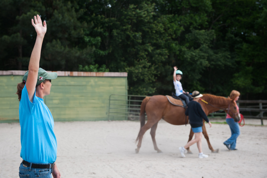 Certified therapeutic riding instructor Susan Price stretches her right arm, asking her riders to do the same, during a Prancing Horse show at Muddy Creek Farm off Trails End Road on Thursday, May 14, 2015 in Whispering Pines, North Carolina.