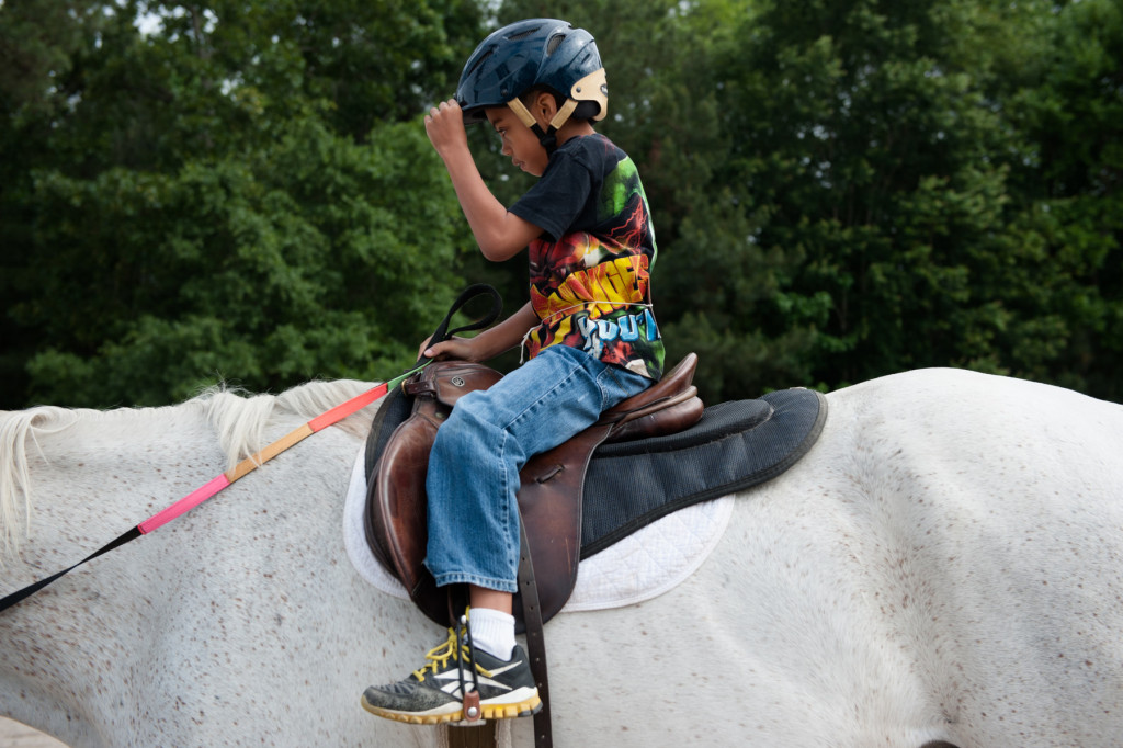 Seven-year-old Elijah Grady straightens the rim of his riding helmet during a Prancing Horse show at Muddy Creek Farm off Trails End Road on Thursday, May 14, 2015 in Whispering Pines, North Carolina.