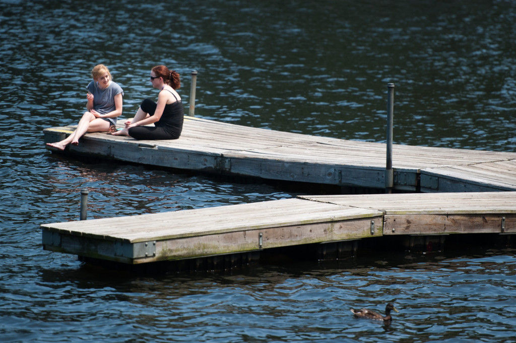 Rachel Whilden (left) and Rachael Davis (center) sit and chat on the dock at Reservoir Park on Tuesday, June 30, 2015 in Southern Pines. Whilden and Davis work together at Bonefish Grill and spend their free time at the park.