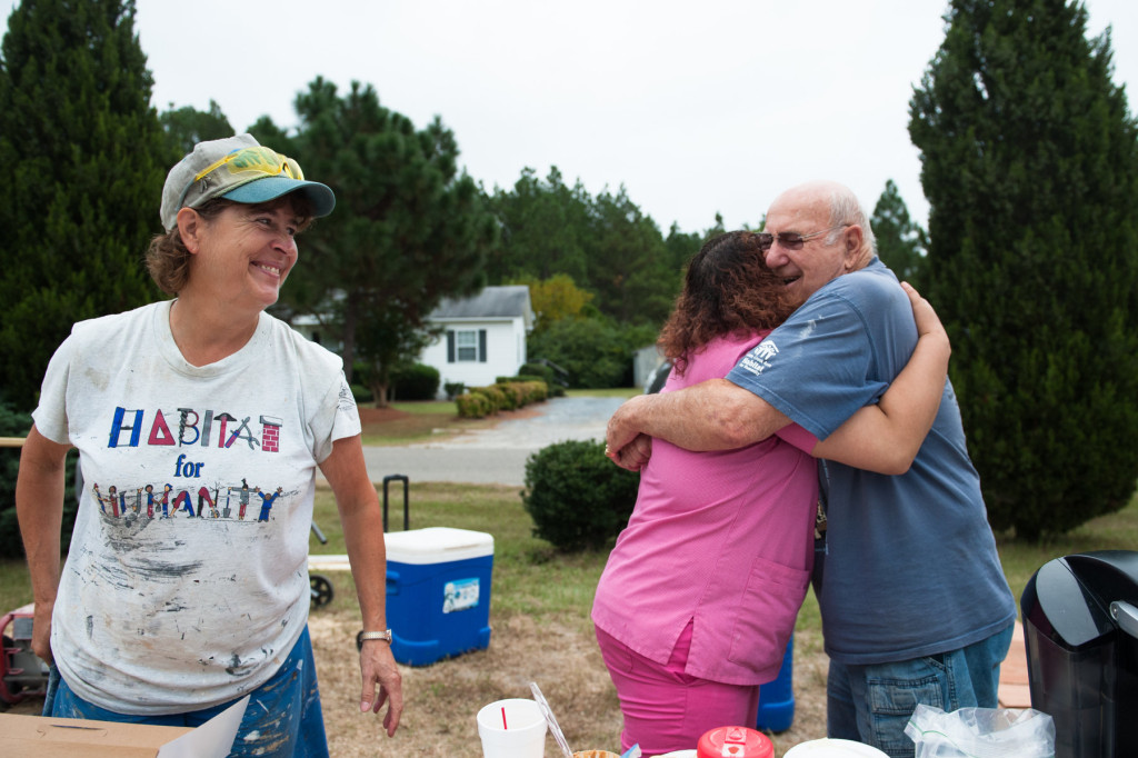 Soon-to-be Homeowner Roberta Blue hugs team wrangler and organizer Jack Paterek -- who works with the group volunteering their time-- as Stephanie Gray (left) smiles at a Habitat for Humanity site off Fuller's way on Tuesday, September 22, 2015 in Aberdeen, North Carolina.