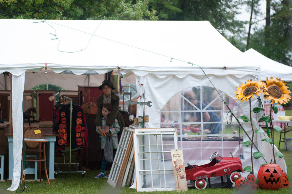 As the rain picks up, Pam West stands under the tent at the Vintage Nook with her granddaughter Ella Hall at the Shaw House Vintage Fair on Saturday, October 10, 2015 at the Historical Shaw House off Morganton Road in Southern Pines, North Carolina.