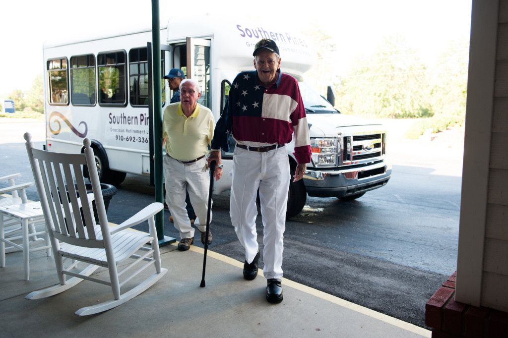 Adrian de Pasquale (center) and Harry Diebold (left) step off the bus to the entrance at the Moore County Airport to attend the Ageless Aviation event where  members of the Southern Pines Gracious Retirement Living Community will take turns riding in Darryl Fisher's Boeing Stearman on Tuesday, September 1, 2015 in Whispering Pines.