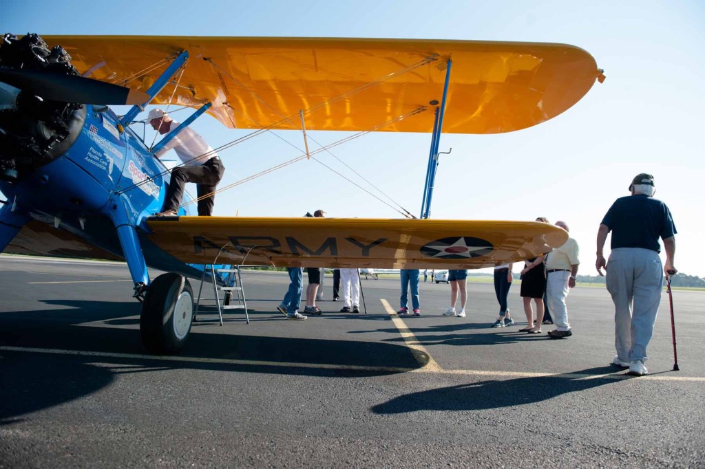 Members with the Southern Pines Gracious Retirement Living Community mingle on the tarmac as they prepare for their rides in Ageless Aviation's Pilot Darryl Fisher's Boeing Stearman biplane at the Moore County Airport on Tuesday, September 1, 2015 in Whispering Pines.