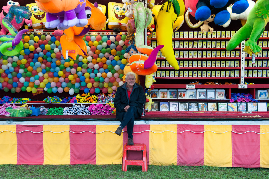 Game operator Jill sits at the Tag Balloon (left) and Quark Gun (right) booths as she waits for players at the Moore County Fair on Thursday, October 1, 2015 in Carthage, North Carolina.