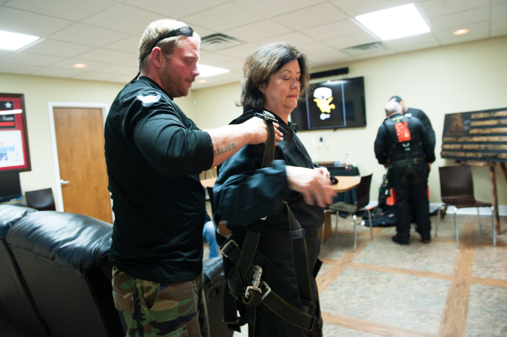 Tandem instructor Robbie Rushton helps Beth Patterson Casilio into her harness and gear as they prep for her tandem jump at the Raeford Drop Zone on Thursday, October 8, 2015 in Raeford, North Carolina.