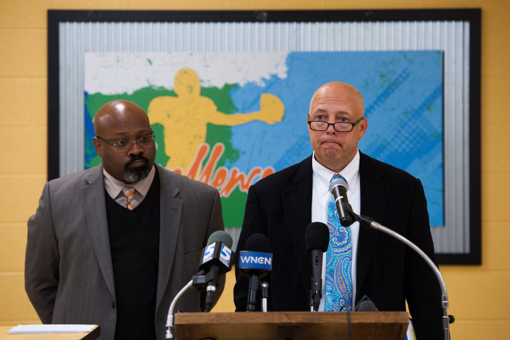 Principal Bob Christina speaks from behind a lectern, with Associate Superintendent of Secondary Education Eric Porter fielding questions from the media, about the violations ruled by the North Carolina High School Athletic Association concerning Pinecrest's football season in the cafeteria, during a press conference, at Pinecrest High School on Monday, November 9, 2015 in Southern Pines, North Carolina.