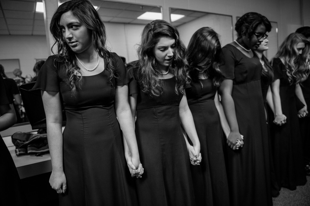 Sarah Tellez (left) and Madalyn Miller (center) hold hands with their fellow choir members as the group recites the Lord's Prayer backstage as they prepare to perform during the Holiday Concert in the Robert Lee Auditorium at Pinecrest High School on Saturday, December 12, 2015 in Southern Pines, North Carolina. The show was presented by the choral department featuring the Chamber Ensemble, Bella Voce, Concert Choir and the Holiday Madrigals.