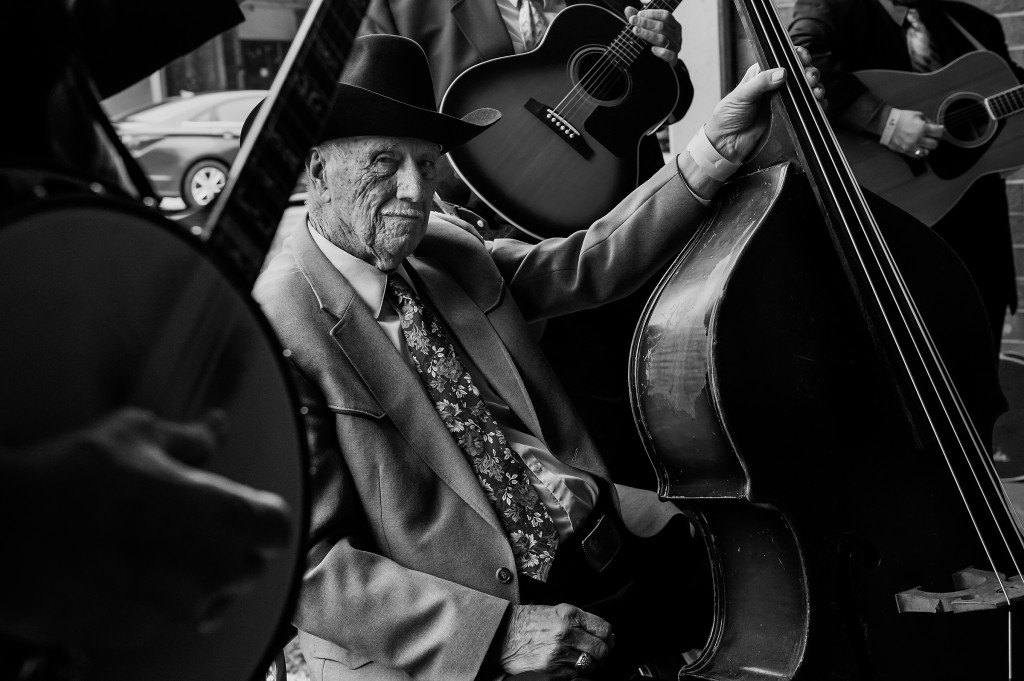 Ninety-year-old Theron Caviness sits with a bass as he waits outside of the auditorium before competing during the 80th Annual Fiddler's Convention at North Moore High School on Saturday, March 14, 2015 in Robbins, North Carolina.