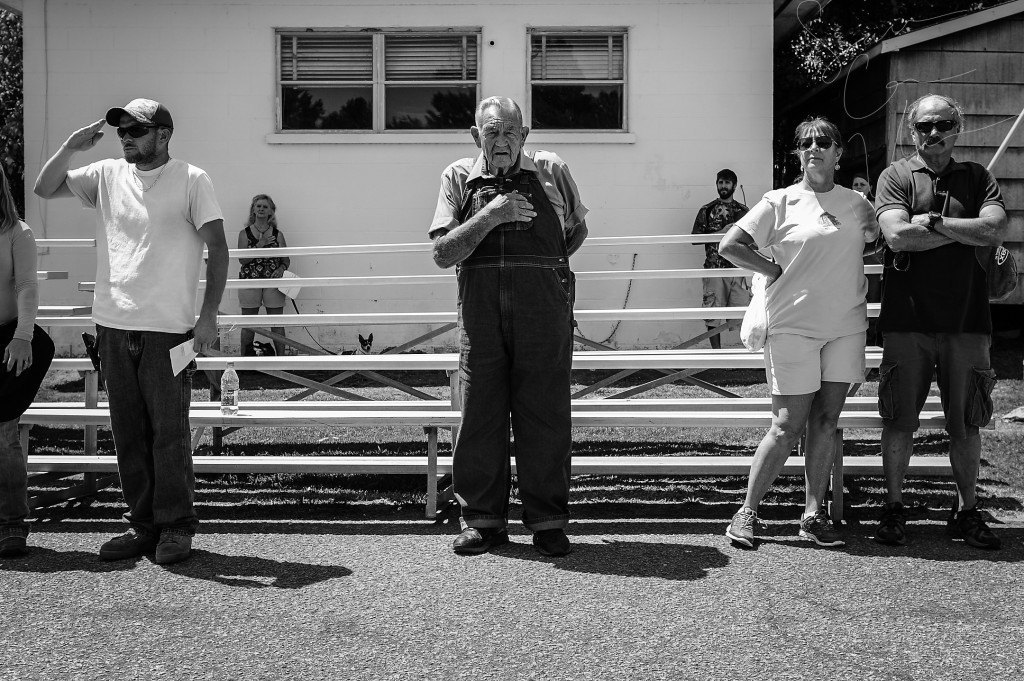 Odell Hussey (center), the wagonmaster and leader of the parade -who has been the leader for sixty-years- places his hand over his heart during the singing of the National Anthem and pledge of Allegiance before the beginning of the trophy ceremony during the 60th annual Farmer's Day celebration and in the downtown area on August 1, 2015 in Robbins, North Carolina. Trophies were awarded for Best Pony, Best Buggy, Oddest Rig and a variety of other titles.