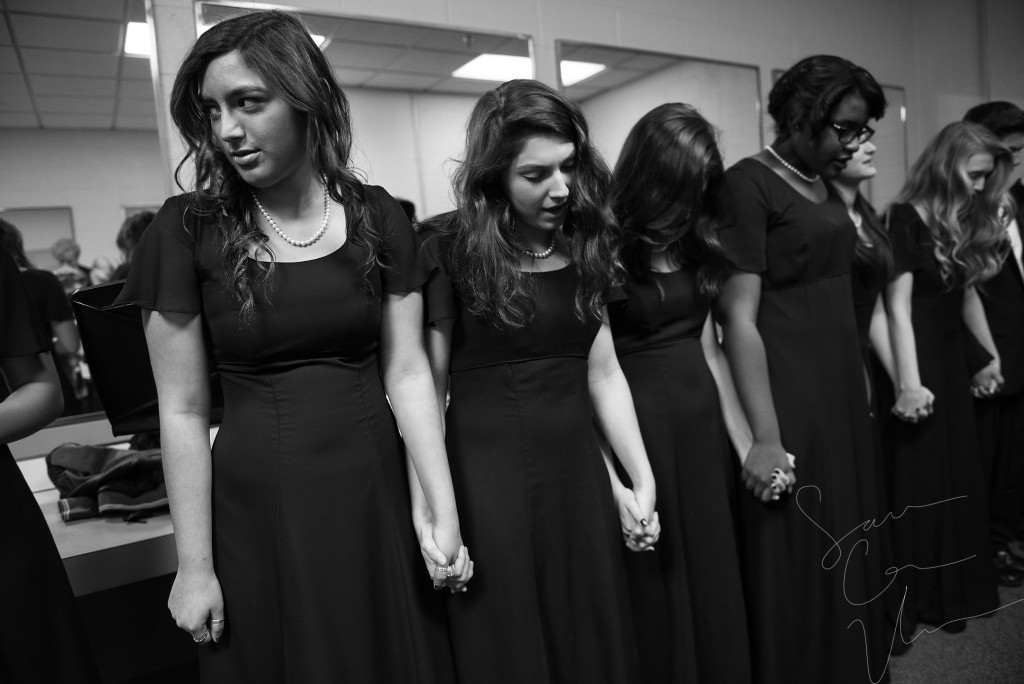 Sarah Tellez (left) and Madalyn Miller (center) hold hands with their fellow choir members as the group recites the Lord's Prayer backstage as they prepare to perform during the Holiday Concert in the Robert Lee Auditorium at Pinecrest High School on Saturday, December 12, 2015 in Southern Pines, North Carolina. The show was presented by the choral department featuring the Chamber Ensemble, Bella Voce, Concert Choir and the Holiday Madrigals.