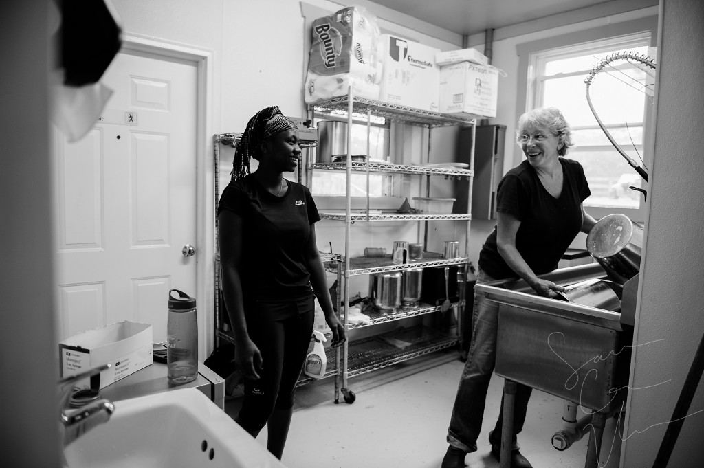 Paradox Farm owner Sue Stovall and volunteer Tema Toure share a moment of laughter as they clean the milking equipment after milking 21 goats at Paradox Farm on Tuesday, July 14, 2015 in West End, North Carolina.